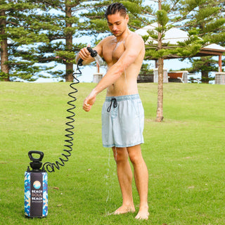 Man using Beach Soul pressurized portable shower at an outdoor campsite
