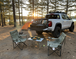 VOZ portable camp kitchen on a pickup truck tailgate at a lakeside campsite with tent and outdoor dining area